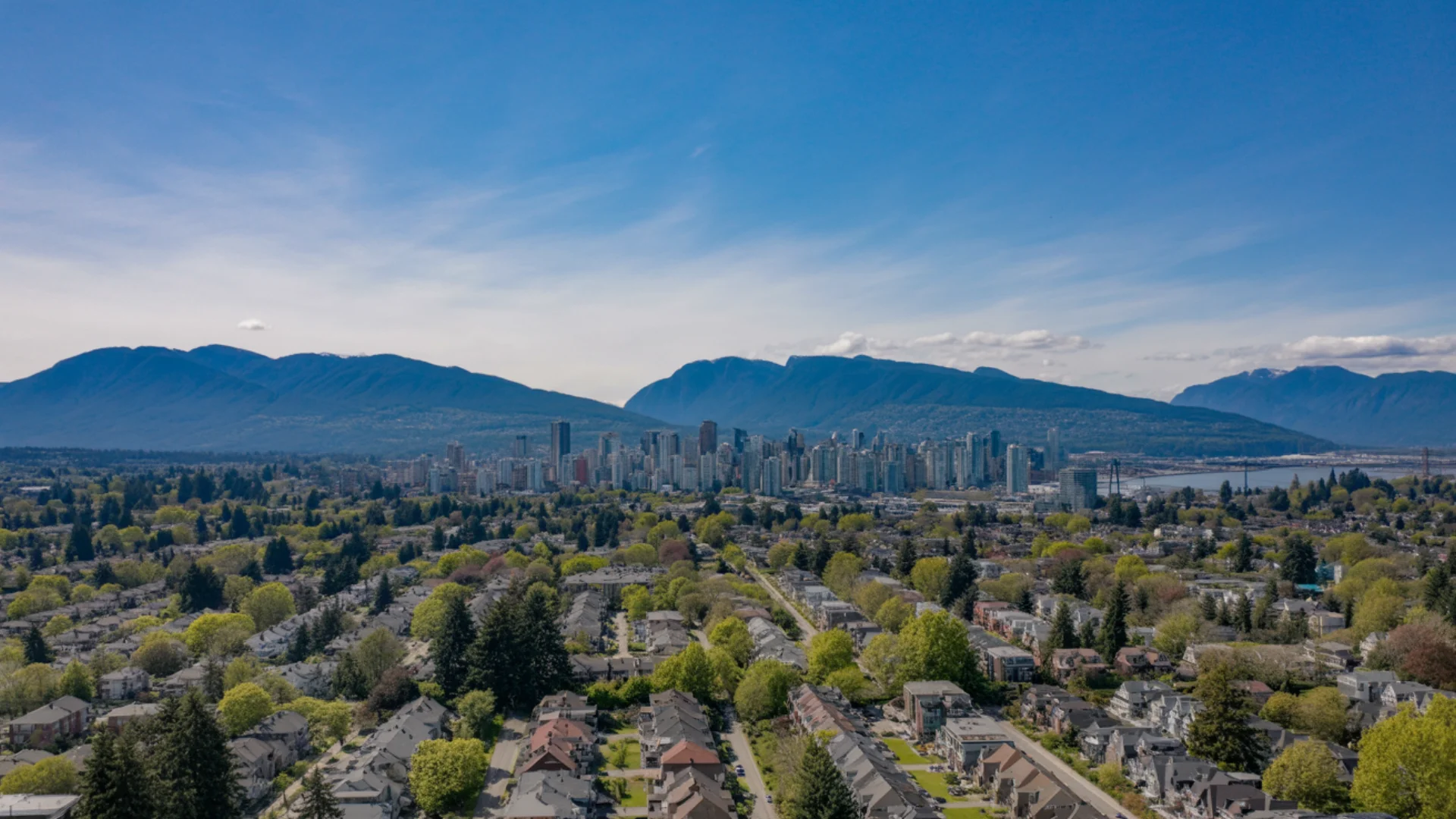 Aerial panoramic view of Vancouver cityscape with mountains and residential neighborhoods